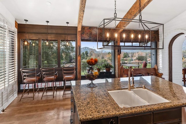 kitchen with pendant lighting, sink, a center island with sink, and stone counters