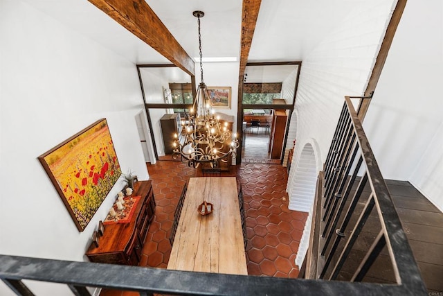 dining area featuring beamed ceiling, dark tile patterned floors, and an inviting chandelier