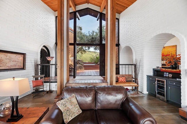 living room featuring wine cooler, dark hardwood / wood-style flooring, high vaulted ceiling, and brick wall