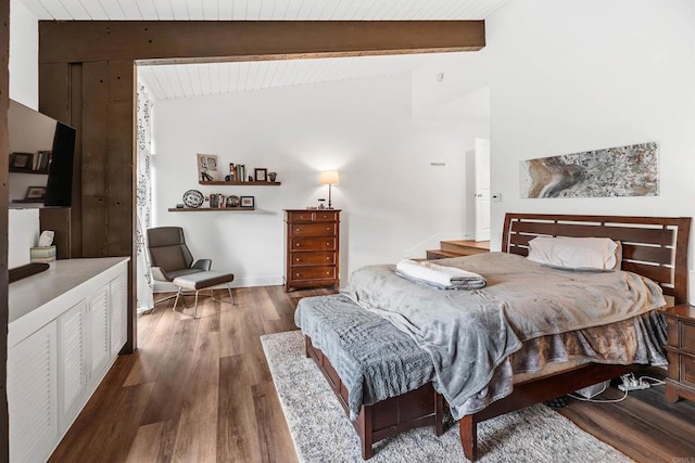 bedroom featuring vaulted ceiling with beams and hardwood / wood-style flooring