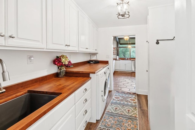 laundry room featuring sink, washer and clothes dryer, cabinets, and light wood-type flooring