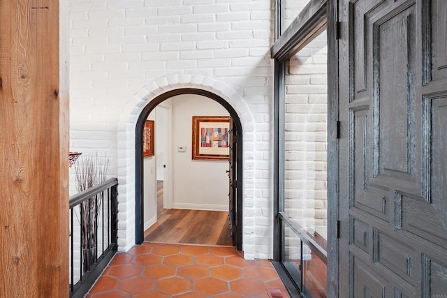 corridor featuring tile patterned floors and brick wall