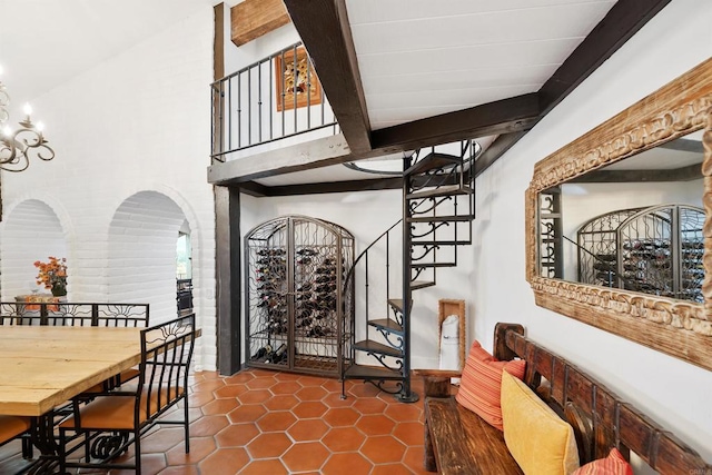 dining area with an inviting chandelier, dark tile patterned flooring, and beam ceiling