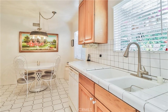 kitchen featuring sink, white dishwasher, tasteful backsplash, decorative light fixtures, and tile countertops