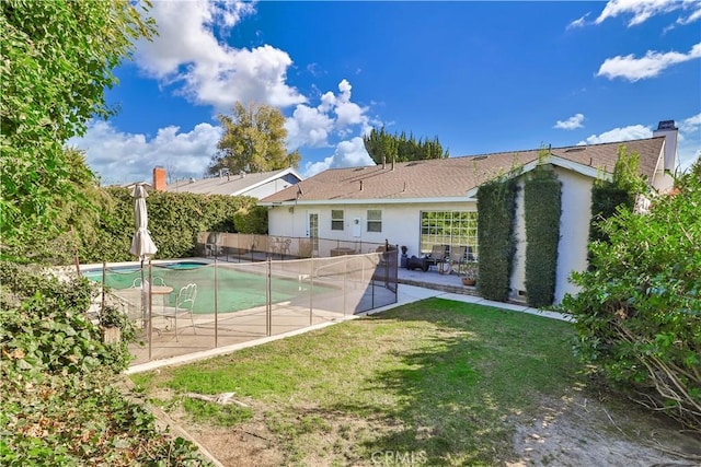 rear view of property with a yard, a fenced in pool, and a patio area