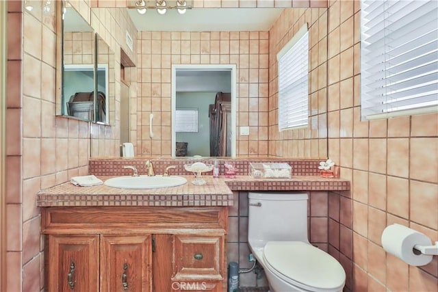 bathroom with vanity, tile walls, and toilet