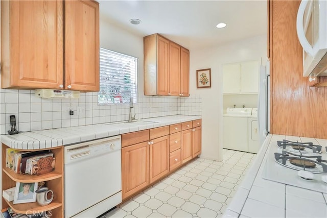 kitchen featuring sink, tile counters, white appliances, washer and clothes dryer, and decorative backsplash