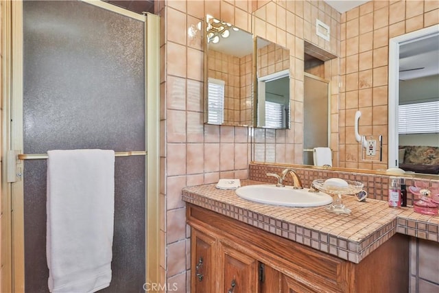 bathroom with tasteful backsplash, vanity, an enclosed shower, and tile walls