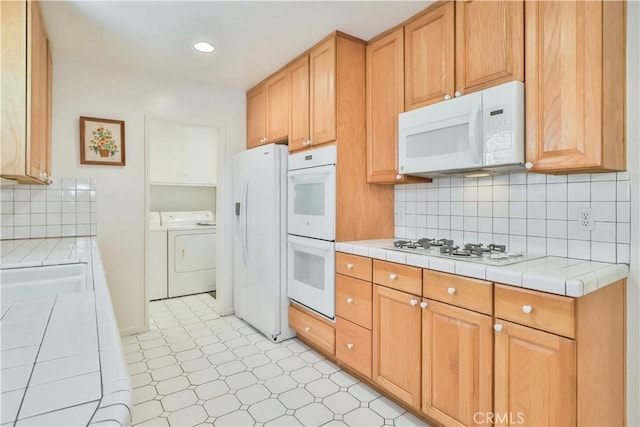 kitchen featuring washer and clothes dryer, sink, tile countertops, and white appliances