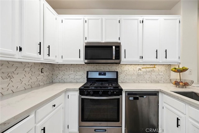 kitchen featuring white cabinetry, backsplash, light stone counters, and stainless steel appliances