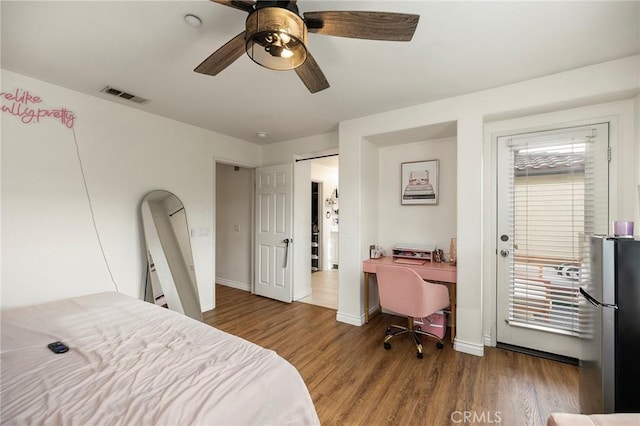 bedroom featuring multiple windows, hardwood / wood-style flooring, stainless steel refrigerator, and ceiling fan