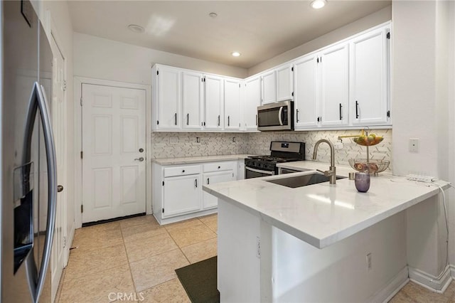 kitchen with white cabinetry, sink, decorative backsplash, kitchen peninsula, and stainless steel appliances