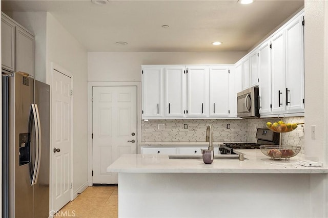 kitchen with white cabinetry, appliances with stainless steel finishes, sink, and kitchen peninsula