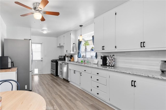 kitchen with sink, white cabinetry, appliances with stainless steel finishes, pendant lighting, and backsplash