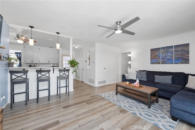 living room featuring ceiling fan, plenty of natural light, and light hardwood / wood-style flooring