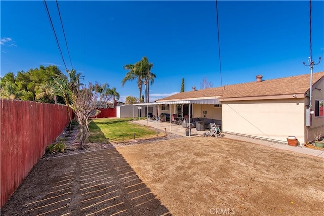 back of property with a patio, a lawn, and a storage shed