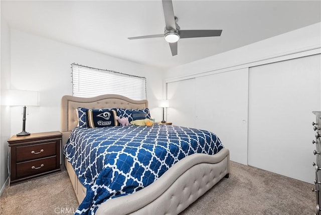 bedroom featuring light colored carpet, ceiling fan, and a closet