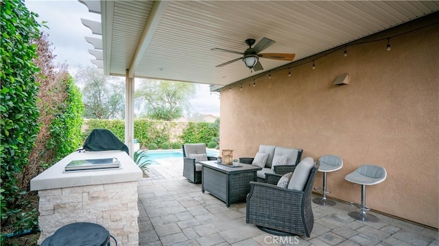 view of patio / terrace featuring ceiling fan and an outdoor living space with a fire pit