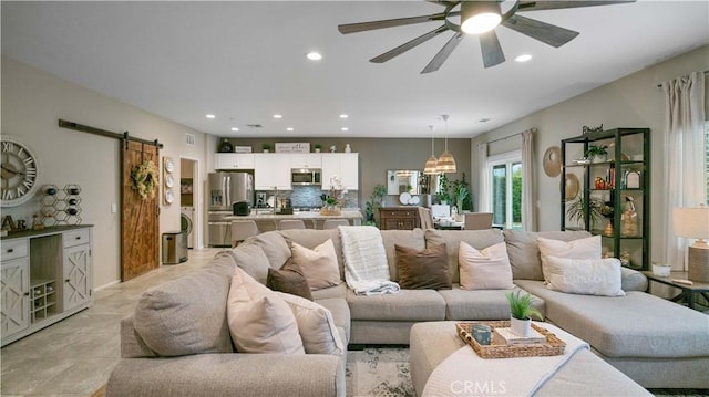 living room with ceiling fan and a barn door