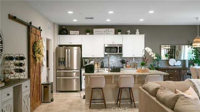 kitchen featuring white cabinetry, pendant lighting, a barn door, and appliances with stainless steel finishes