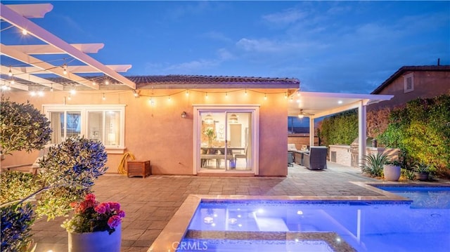 back house at dusk with area for grilling, a pergola, a patio area, and ceiling fan