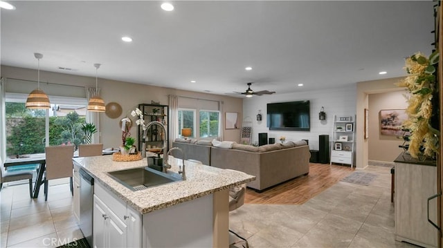 kitchen with sink, dishwasher, hanging light fixtures, an island with sink, and white cabinets