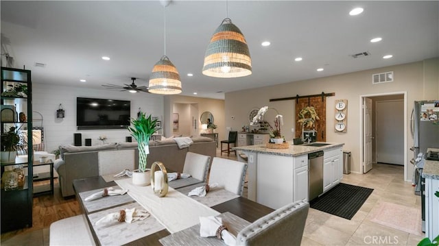 dining area featuring ceiling fan, a barn door, and sink