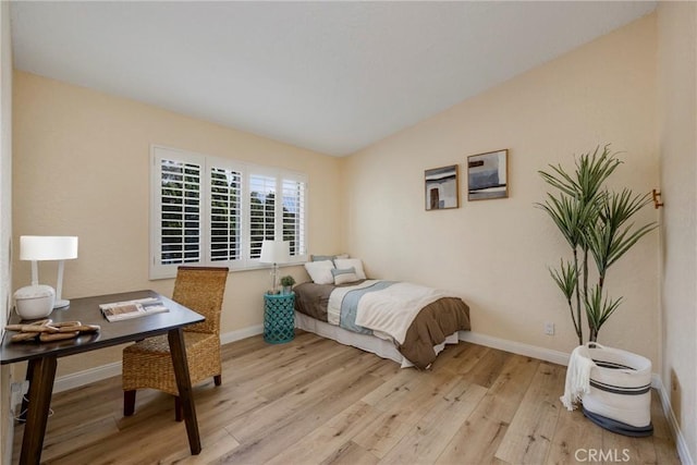 bedroom featuring light wood-style flooring, baseboards, and vaulted ceiling