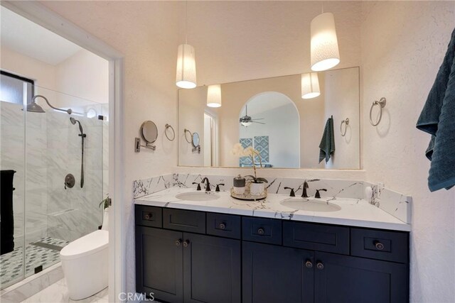 full bathroom featuring toilet, a stall shower, double vanity, and a sink