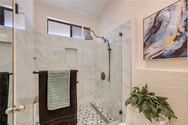 bathroom featuring a textured wall and a shower stall