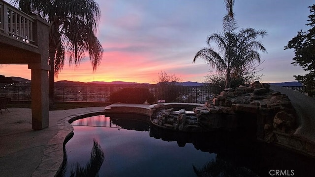 pool at dusk featuring a patio and a mountain view