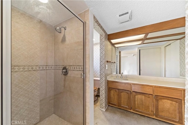 bathroom featuring vanity, a textured ceiling, a shower with door, and toilet