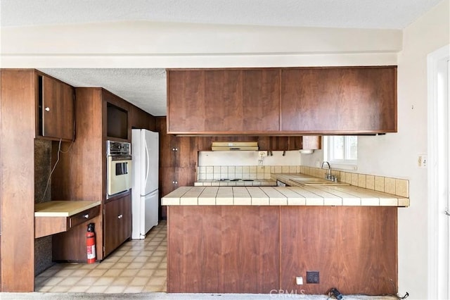 kitchen featuring extractor fan, sink, tile countertops, and white appliances