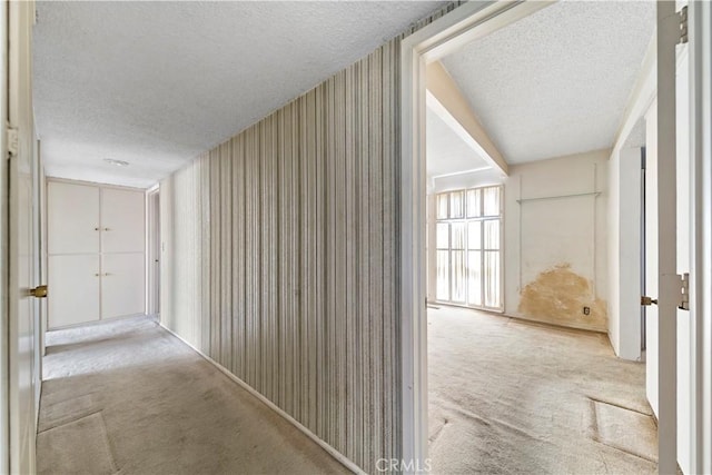 corridor with light colored carpet and a textured ceiling