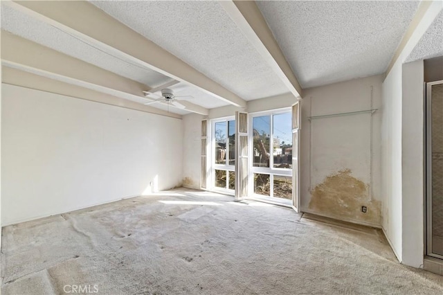 spare room featuring beamed ceiling, ceiling fan, light carpet, and a textured ceiling