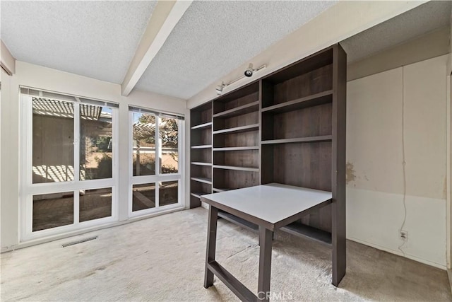 home office featuring beam ceiling, carpet flooring, and a textured ceiling