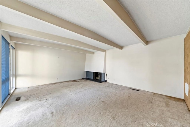 unfurnished living room with beamed ceiling, a multi sided fireplace, carpet flooring, and a textured ceiling