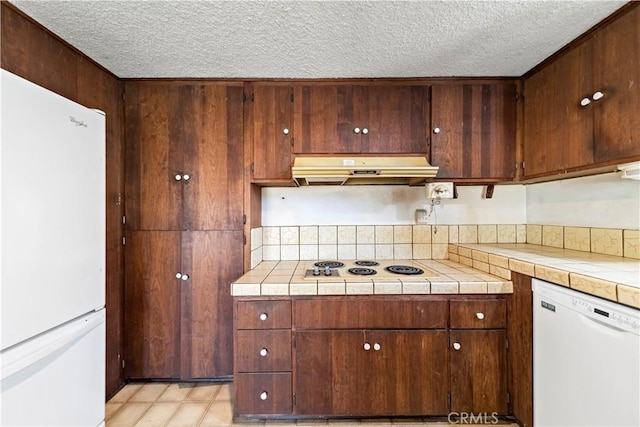 kitchen with tile counters, a textured ceiling, and white appliances