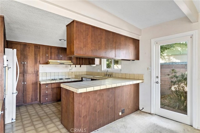 kitchen with sink, tile counters, white appliances, kitchen peninsula, and a textured ceiling