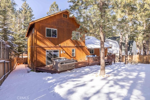 snow covered house featuring a wooden deck and a jacuzzi