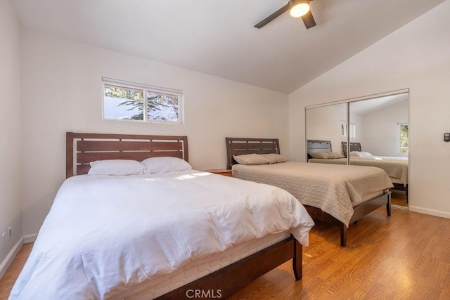 bedroom featuring multiple windows, hardwood / wood-style floors, vaulted ceiling, and a closet