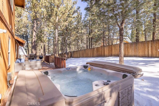 snow covered patio featuring a hot tub and area for grilling