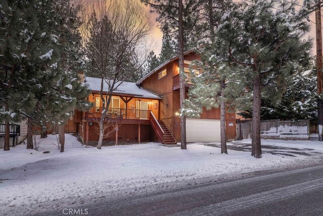 snow covered property featuring a garage and covered porch