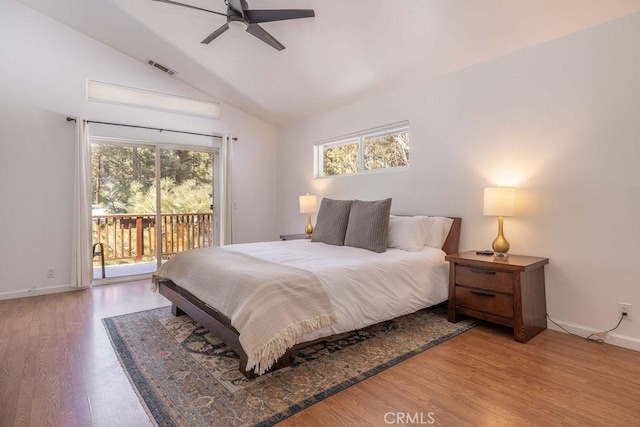 bedroom with vaulted ceiling, access to exterior, light hardwood / wood-style floors, and multiple windows