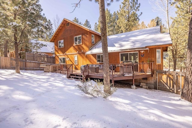 snow covered house featuring a wooden deck