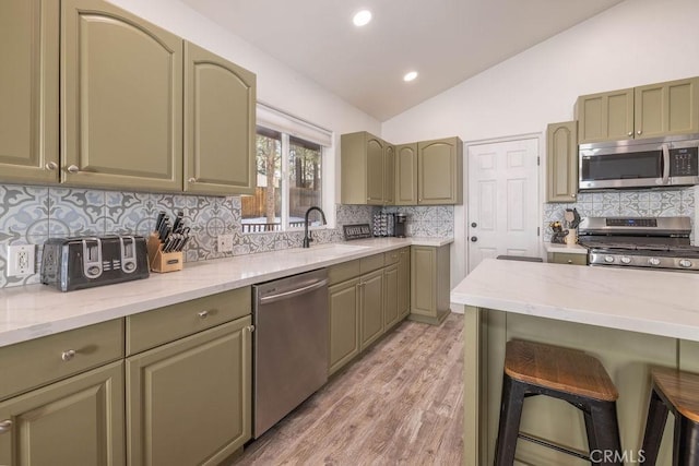 kitchen with green cabinetry, stainless steel appliances, sink, and vaulted ceiling