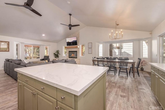 kitchen with light hardwood / wood-style flooring, a center island, a fireplace, green cabinetry, and ceiling fan with notable chandelier