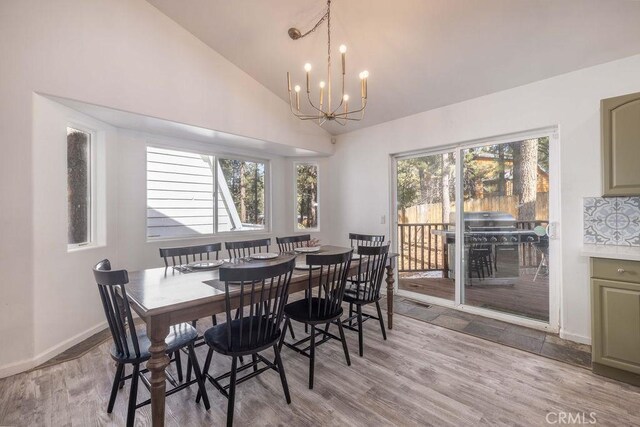 dining space with plenty of natural light, lofted ceiling, light hardwood / wood-style floors, and a notable chandelier