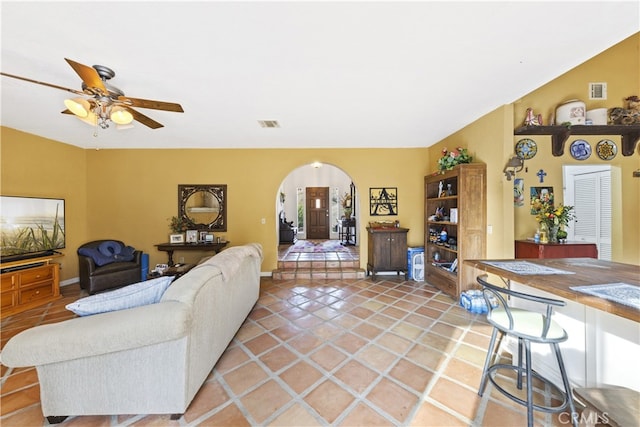 living room with ceiling fan, tile patterned flooring, and vaulted ceiling