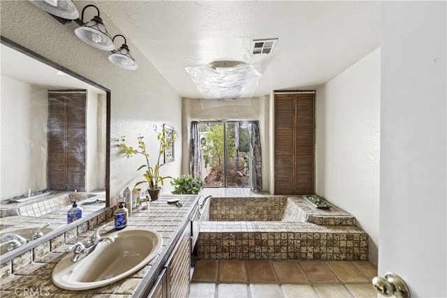 bathroom featuring vanity, a bath, and a textured ceiling